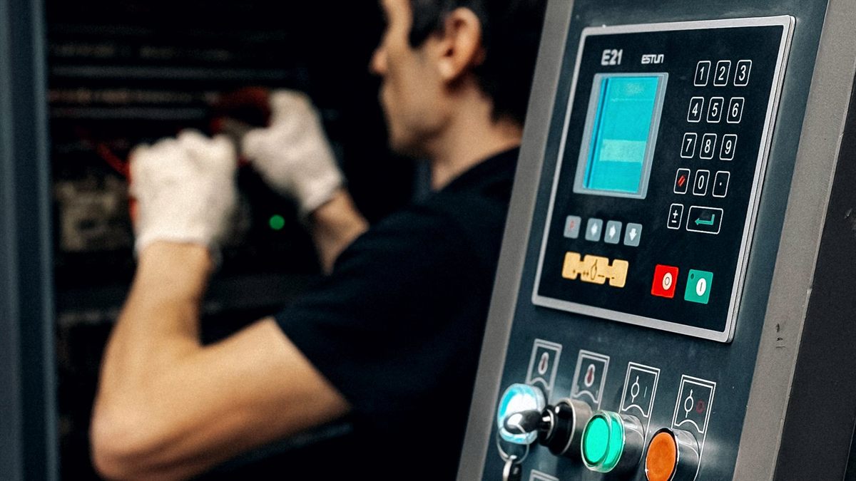 Operario ante el panel de control de una máquina industrial